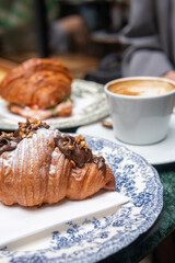 Parisian style breakfast with coffee served in fine blue china and on a marble green table. Delicious sweet chocolate croissant, savoury croissant and cappuccino. Copy space