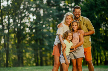 Portrait of a cheerful family standing together in nature and smiling.