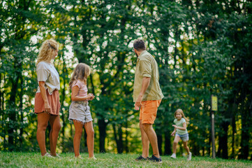 Fototapeta premium Parents and big sister are waiting for a girl who is running to them in nature.