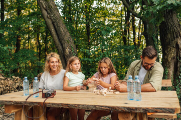Cheerful family is spending day in nature and playing board game.