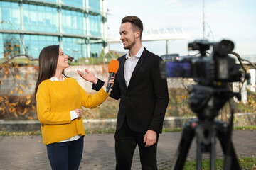Young journalist interviewing businessman on city street