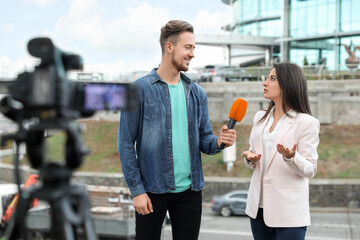 Young journalist interviewing businesswoman on city street