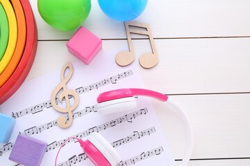 Notes, music sheet, headphones and toys on white wooden table, flat lay with space for text. Baby...
