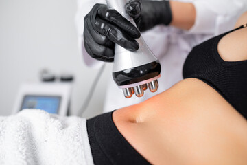 RF body cavitation lifting procedure to reduce fat in belly to young woman in a beauty salon 