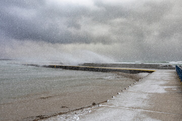 Waves crash into the pier at the beach in Port Elgin, Ontario during a winter snow storm.