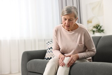 Arthritis symptoms. Woman suffering from pain in knee at home