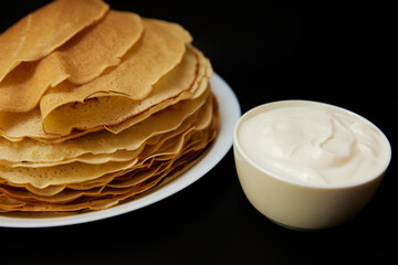 Thin pancakes with sour cream on board