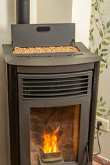 Vertical image of a modern pellet stove with the hopper full to overflowing, ecological and sustainable heat, renewable energy