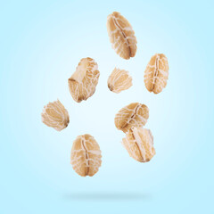 Rolled oat flakes falling on light blue background
