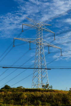 power lines at geen fields with a beautiful and cloudy sky behind