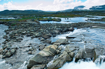 Beautiful landscape seeing from dam of the outlet of Lake Finsevatnet, snowy mountains and The Blue Ice (Blaisen) ice field located in Hardangerjokulen glacier in Finse, Norway