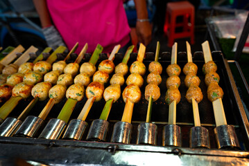 Top view and low light. Fish balls with bamboo which is toasting on the stove. That are sold at street food in seaside area of Thailand.