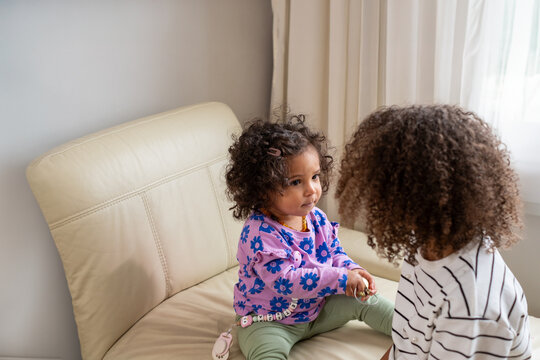 Two mixed race siblings are thoughtfully looking at each other, A picture for national siblings day and sisterhood, used for friendships between sisters and siblings .