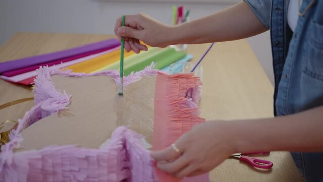Hispanic woman making colorful pinata in small business studio