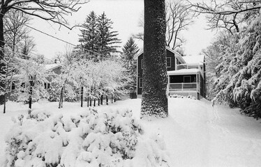 suburban house and driveway covered with snow after the snow storm in late winter in black and white