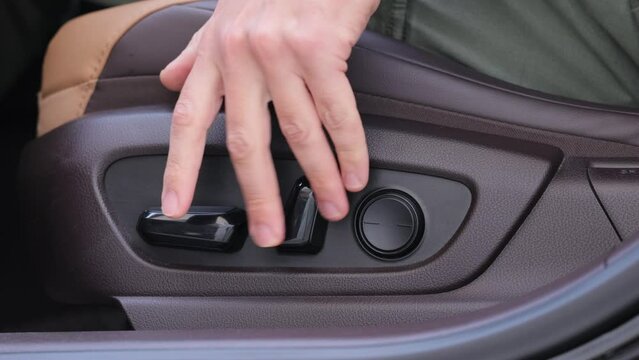 Driver's seat adjustment buttons. Buttons for adjusting seat position. Car interior. Male Hand Presses Down the Furniture Adjustment Button Motion Activated Power Seat Expensive Brown Leather