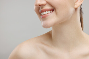 Obraz na płótnie Canvas Beauty concept. Smiling woman on grey background, closeup