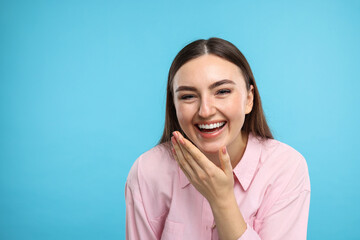 Beautiful woman laughing on light blue background. Space for text