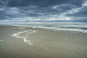 Dark clouds over sandy beach on the North Sea coast of the Netherlands - 750193388