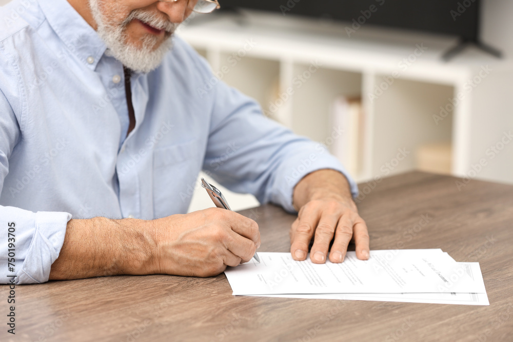 Poster Senior man signing Last Will and Testament at wooden table indoors, closeup