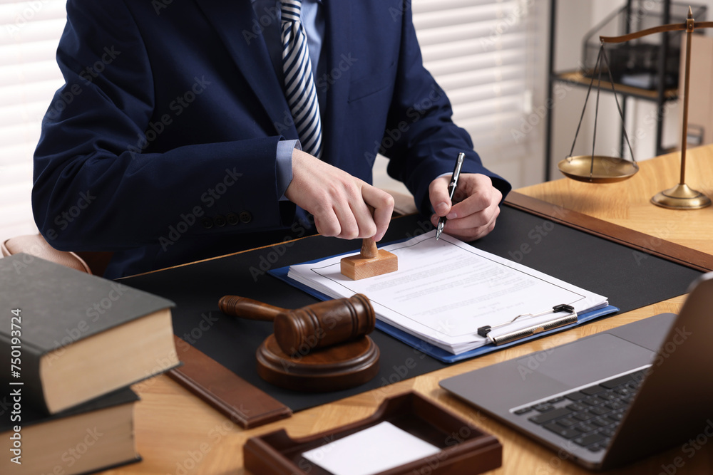 Canvas Prints Notary with pen stamping document at wooden table in office, closeup