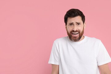 Obraz premium Portrait of surprised man on pink background, space for text