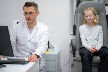 doctor and young patient in eye clinic, girl undergoing an eye test with professional optometrist...