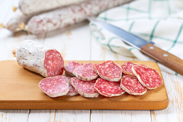 traditional Spanish salami fuet sausage or dry sausage cut in slices in a kitchen table.