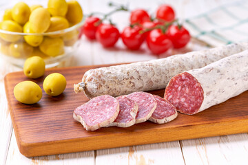 traditional Spanish salami fuet sausage with rosemary and baguet  on a cutting board close up.