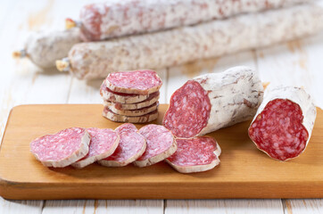 slices traditional Spanish salami fuet sausage or dry sausage covered fermented mold  in a wooden table.