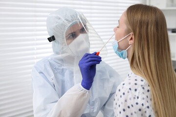 Naklejka premium Laboratory testing. Doctor in uniform taking sample from patient's nose with cotton swab at hospital