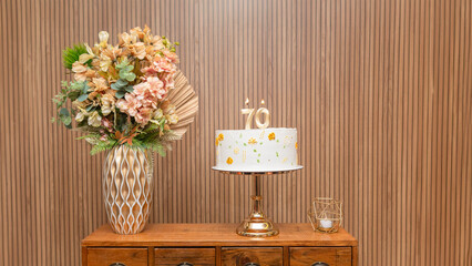 A 70th birthday cake on a decorated table with a vase of colorful flowers





