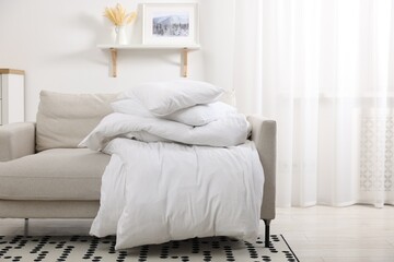 Soft pillows and duvet on sofa indoors, space for text