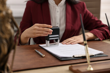 Notary stamping document at table in office, closeup