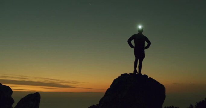 Man, hiking and silhouette on hill at night, exercise and confidence for workout achievement in outdoors. Male person, sky background and pride for fitness, adventure and freedom in dark on mountain