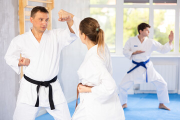Fototapeta premium Woman and man in kimono sparring together in gym during karate training