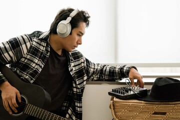 Latin man playing acoustic guitar at home reading notes