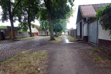 Nicht asphaltierter Gehweg an einer Kopfsteinpflaster-Strasse