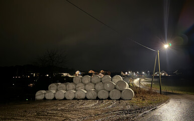 A bunch of plastic rolled hay bales in the dark