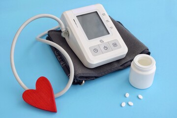 Tonometer for measuring blood pressure and pills, heart on a blue background.  Hypertension day, world heart day, world health day