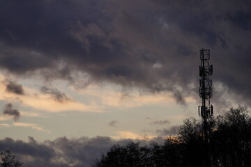 Wieża przekaźnikowa na tle dramatycznego pochmurnego nieba oraz drzew - obrazy, fototapety, plakaty