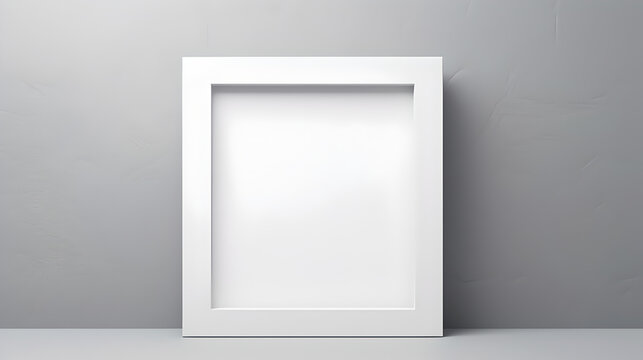 mockup template poster: empty white square picture frame standing on desk behind clean grey wall background