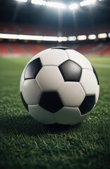 Fototapeta premium Soccer ball rests on grass of green field in front of majestic lit up, creating exciting atmosphere stadium. Scene captures essence of game, ready for action, excitement. Advertising, banner, print.