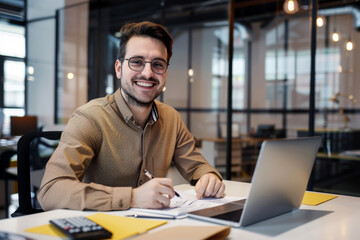 Fototapeta na wymiar Portrait of young businessman in shirt, man smiling and looking at camera at workplace inside office, accountant with calculator behind paper work signing contracts and financial reports