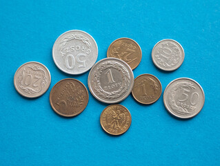 Polish metallic money on the blue background, close up. Zloty and groszy coins made from cupronickel and from aluminium bronze