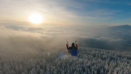 Dream flying paragliding above foggy clouds in winter forest nature, freedom adrenaline adventure