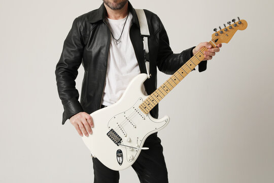 Cropped image of rock musician plays guitar and posing over white background. 