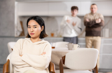 Fototapeta premium Adult and young men quarreling with young woman in kitchen at home