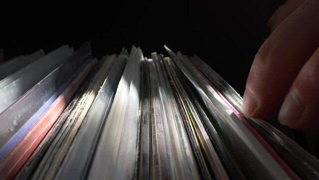 Browsing through vinyl records collection in a crate side view