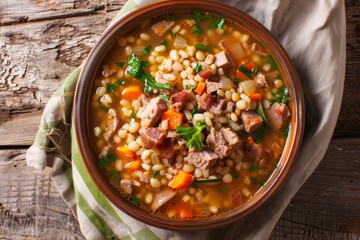 Close up top view of homemade Ricet barley and bean soup with smoked meat and vegetables in a bowl on the table